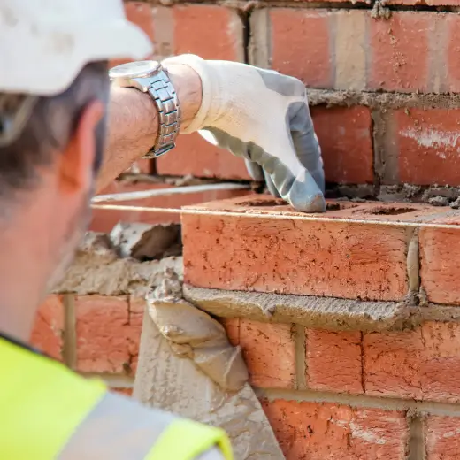 Bricklayer laying bricks on a UK construction site representing trade businesses using Elite Connector CRM